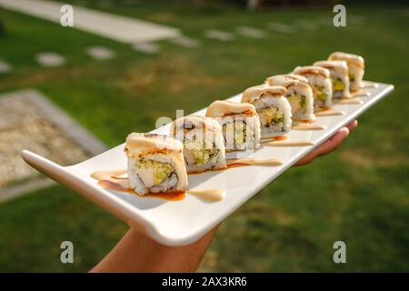 Primo piano di qualcuno che tiene un vassoio di diversi tipi di sushi Foto Stock
