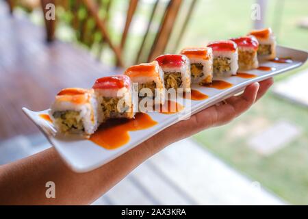 Primo piano di qualcuno che tiene un vassoio di diversi tipi di sushi Foto Stock