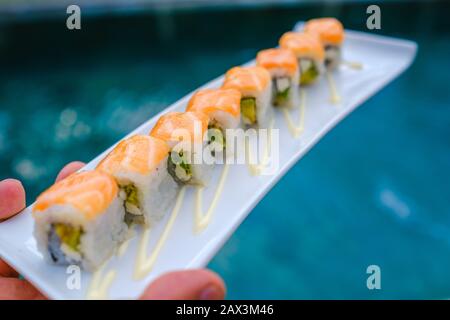 Primo piano di qualcuno che tiene un vassoio di diversi tipi di sushi Foto Stock