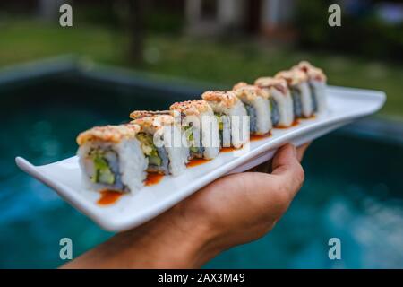 Primo piano di qualcuno che tiene un vassoio di diversi tipi di sushi Foto Stock