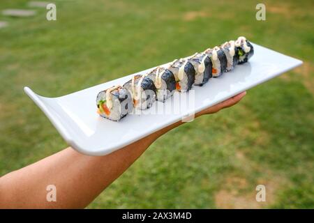 Primo piano di qualcuno che tiene un vassoio di diversi tipi di sushi Foto Stock