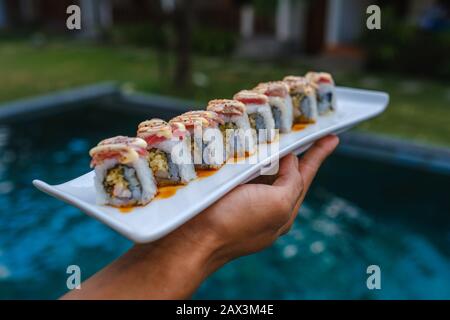 Primo piano di qualcuno che tiene un vassoio di diversi tipi di sushi Foto Stock