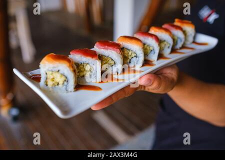 Primo piano di qualcuno che tiene un vassoio di diversi tipi di sushi Foto Stock