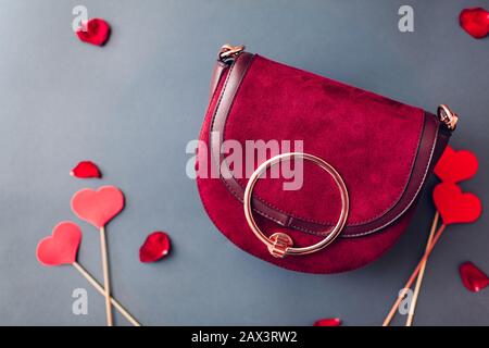 Regalo di San Valentino. Borsetta femminile con petali di rosa e cuori rossi. Elegante borsa borgogna con fiori. Moda. Foto Stock