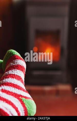 Piedi gambe in inverno abiti calze di lana a camino sfondo. Donna seduta a casa in inverno o in autunno relax serale e in fase di riscaldamento. Inverno e freddo concetto. Hygge vigilia di Natale Foto Stock