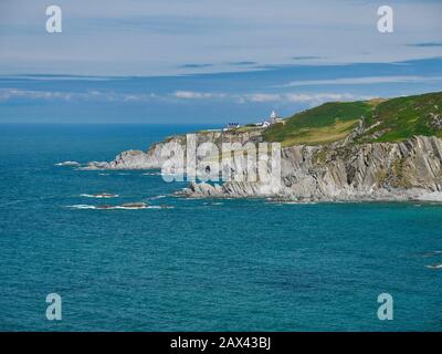 La costa settentrionale del Devon a Bull Point, che mostra il faro e gli annessi. La strata di ardesia ripidamente inclinata della Formazione Di Morte Slates è visib Foto Stock