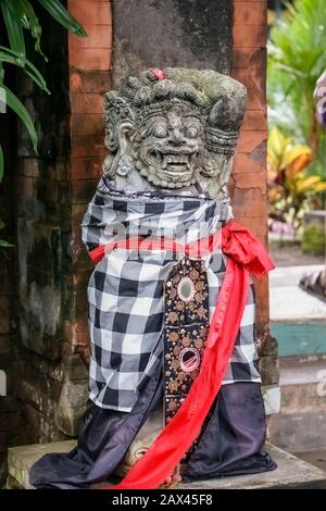 Una statua in pietra di un demone indù o dio vestito nel tradizionale poleng saput - bianco e nero tessuto controllato. Bali, Indonesia. Quando un oggetto è noi Foto Stock