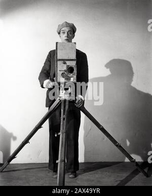 1928 , USA : l'attore e regista americano del cinema muto BUSTER KEATON ( 1895 - 1966 ) , in CAMERAMAN ( 1928 ) - SILENT MOVIE - CINEMA MUTO - ritratto - ritratto - registrazione filmato - attore - comico - COMICO - scarpe - cappello - CAPPELLO - ANNI TRENTA - '30 - camera - macchina da presa - cavalletto - tripode - operatore filmato --- ARCHIVIO GBB Foto Stock