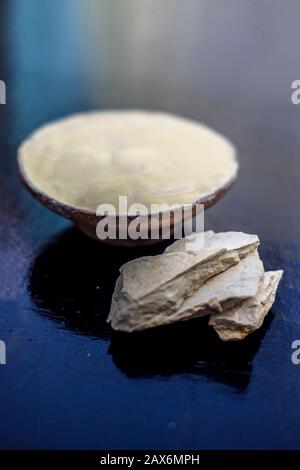 Primo piano di multani misti mitti o mullani mitti o terra più piena in una ciotola di argilla su superficie di legno con argilla grezza da multan. Scatto verticale. Foto Stock