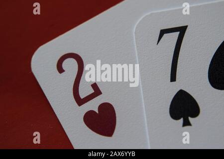 Primo piano di due e sette carte sotto le luci contro uno sfondo rosso Foto Stock