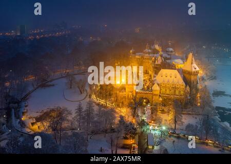 Budapest, Ungheria - veduta aerea del castello di Vajdahunyad innevato nel Parco cittadino con il grazioso mercato di Natale all'ora blu Foto Stock