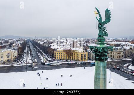 Budapest, Ungheria - veduta aerea della Piazza degli Eroi innevati con la scultura dell'angelo e via Andrassy in una mattinata invernale Foto Stock