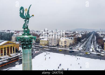 Budapest, Ungheria - veduta aerea della Piazza degli Eroi innevati con la scultura dell'angelo e via Andrassy in una mattinata invernale Foto Stock