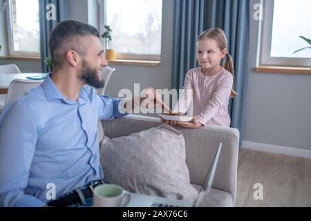 Figliola di cura che tratta il papà con i biscotti. Foto Stock