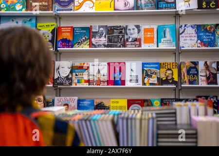 Katowice, Polonia - 6-8 dicembre 2019: Ragazzo di fronte alla mensola del libro in cerca di libri durante la Fiera del libro della Slesia a Katowice 2019 Foto Stock