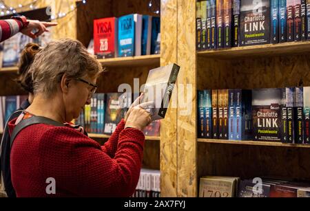 Katowice, Polonia - 6-8 dicembre 2019: Donna che legge Charlotte link descrizione del libro durante la Fiera Silesiana del libro a Katowice nel 2019 presso International Co Foto Stock