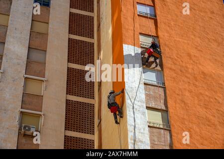 Accesso alla corda lavoratori pittura torre-blocco luminoso arancione, Villajoyosa, Costa Blanca, Spagna Foto Stock