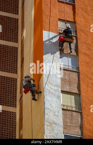 Accesso alla corda lavoratori pittura torre-blocco luminoso arancione, Villajoyosa, Costa Blanca, Spagna Foto Stock