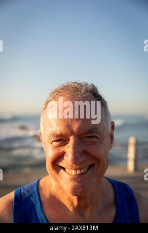 Jogger sorridente e guardando la macchina fotografica sul mare Foto Stock