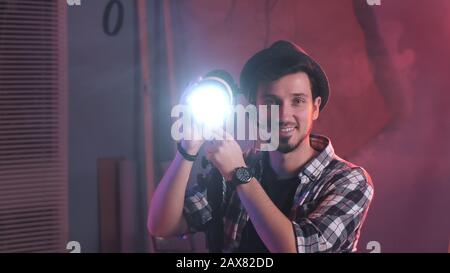 Primo piano della lampada di rotazione dell'impugnatura della chiave verso la fotocamera e iniziare a sorridere. C'è luce rossa in studio cinematografico. Foto Stock