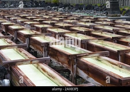 Acqua minerale curativa in scatole di legno di Yubatake onsen, sorgente termale calda nella famosa località montana di Kusatsu, Giappone Foto Stock