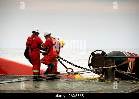 l'equipaggio marino inizia a lavorare sul ponte per l'operazione di movimentazione dell'ancora Foto Stock