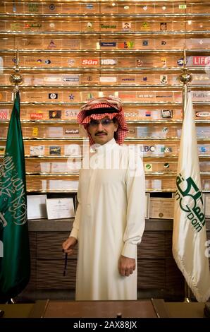 Ritratto di sua altezza reale Principe al Waleed Bin Talal al-Saud alla sua scrivania di fronte ad un muro pieno di loghi aziendali in cui ha partecipazioni al suo ufficio presso la holding del regno, Riyadh, Arabia Saudita. Foto Stock