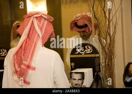 Un'immagine speculare della sua altezza reale il principe al Waleed Bin Talal al-Saud che si apre attraverso una pila di auto-biografie nel suo ufficio presso la Kingdom Holding Company, Riyadh, Arabia Saudita. Foto Stock