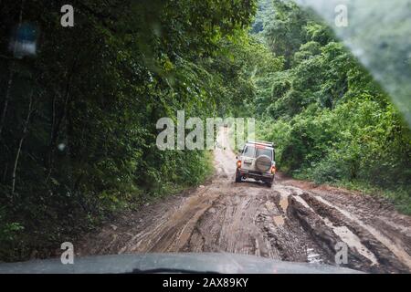 Veicoli sulla strada fangosa Chiquibul alla riserva forestale Mountain Pine Ridge, guida sotto la pioggia per Caracol, rovine Maya, Cayo District, Belize, America Centrale Foto Stock