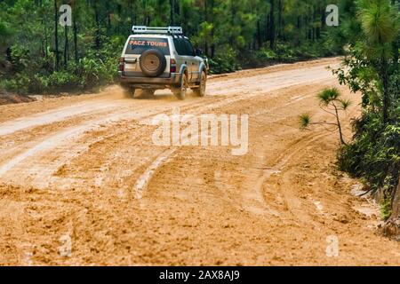 Veicolo su strada fangosa Chiquibul presso la Mountain Pine Ridge Forest Reserve, guida sotto la pioggia per Caracol, rovine Maya, Cayo District, Belize, America Centrale Foto Stock