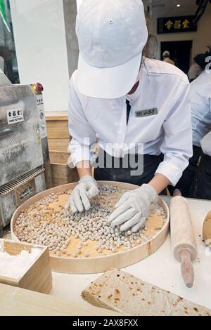 Un giovane americano asiatico fa palle di tapioca per bere una boba nella finestra di Xing fu Tang, un negozio taiwanese sulla Main St. A Flushing, Queens, Chinatown Foto Stock
