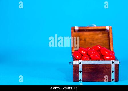 Una cassa del tesoro piena di cuori d'amore, presa su uno sfondo blu brillante. Foto Stock