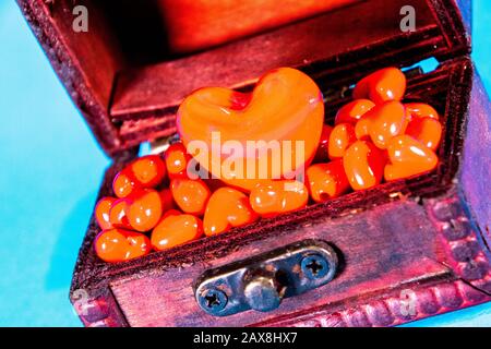 Una cassa del tesoro piena di cuori d'amore, presa su uno sfondo blu brillante. Foto Stock