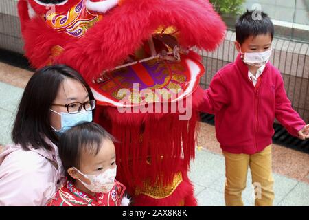 Famiglia Cinese con Maschere Facciali in posa con Lion Dancing Head, Hong Kong durante Lo Scoppio di Coronavirus, 2020. Foto Stock