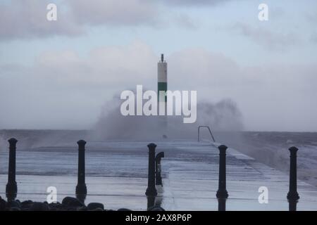 Aberystwyth Wales Ceredigion UK Weather 11th Febuary 2020. Freddo e ventoso con docce e gales costiere che guidano in enormi onde per sferrarsi contro la luce del porto e le difese del mare. Credito: Mike davies/Alamy Live News Foto Stock