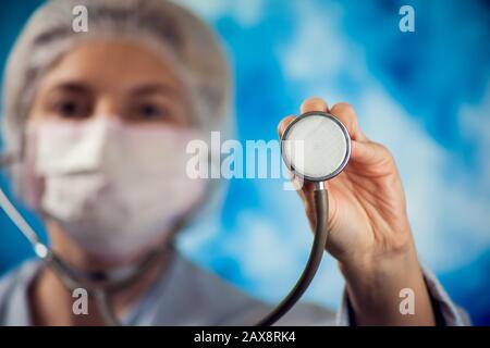 medico femminile in guanti medici blu che tengono il phonendoscopio. Concetto di persone, medicina e assistenza sanitaria Foto Stock