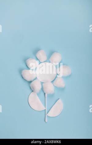 Cotone e bastoni sullo sfondo blu in forma di fiore Foto Stock