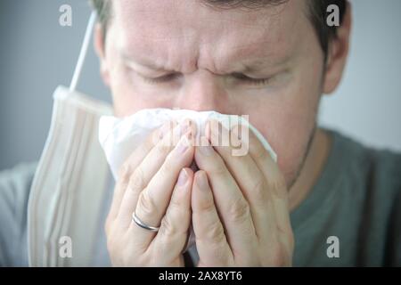 l'uomo viene infettato da virus / l'uomo starnutisce. Foto Stock