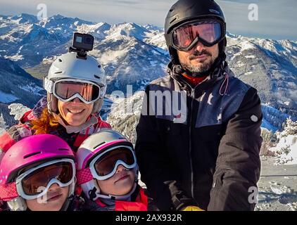 Famiglia godendo le vacanze invernali tenendo selfie in marcia di sci. Famiglia con bambini a sciare vacanza vestito di sci con ingranaggio di caschi da sci e gog Foto Stock