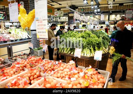 I residenti cinesi locali indossano maschere facciali per la prevenzione del nuovo coronavirus e polmonite negozio di verdure in un supermercato a Lianyungang Cit Foto Stock