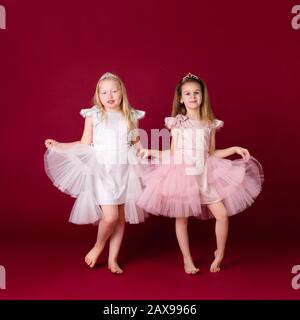 Belle ragazze principessa giocare in lusso rosa, bianco e argento abiti isolato su sfondo rosso. Viso divertente, emozioni diverse. Foto Stock