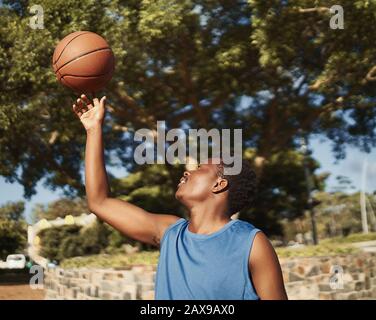 Un giocatore di basket afroamericano che bilancia la palla sulla sua mano nel parco Foto Stock