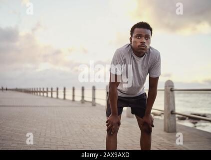 Giovane uomo sportivo afroamericano che si prende una pausa dopo aver corso sul lungomare Foto Stock