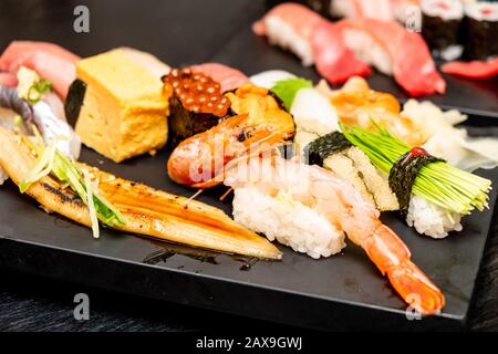 Vero sushi giapponese in un ristorante a Tokyo. Set di sushi su un piatto nero in pietra Foto Stock