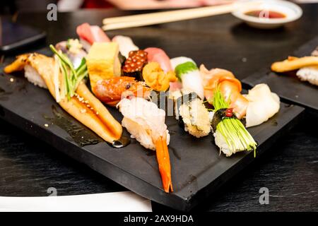 Vero sushi giapponese in un ristorante a Tokyo. Set di sushi su un piatto nero in pietra Foto Stock