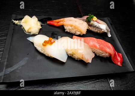 Vero sushi giapponese in un ristorante a Tokyo. Set di sushi su un piatto nero in pietra Foto Stock