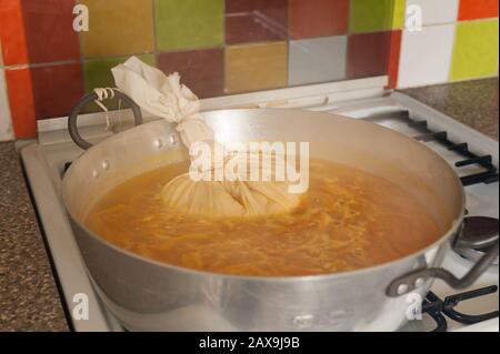 Bollendo giù le arance di Siviglia in un grande marmellata o marmellata che fa la vaschetta che simmering fuori dell'acqua eccedente con il sacchetto di muslin contenente la fonte dei semi di pectina pips Foto Stock