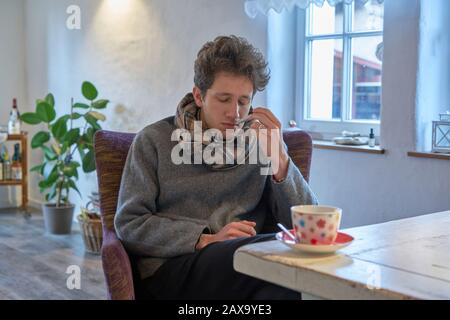 il giovane appare malato ed esausto e ha un termometro in bocca Foto Stock