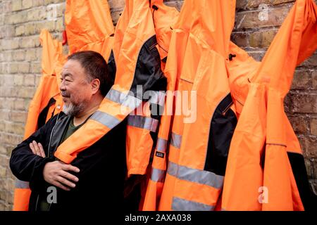 Berlino, Germania. 11th Feb, 2020. Ai Weiwei, artista cinese, presenta la sua opera "Giacche di sicurezza Zipped l'Altro Modo" nel suo studio di fronte al lavoro nella 'parete della versione'. Le varie costruzioni di giacche di sicurezza, ganci e barre di ferro possono essere acquistate come parti individuali dallo sponsor Hornbach e assemblate da parti interessate stesse. Credit: Christoph Soeder/Dpa/Alamy Live News Foto Stock