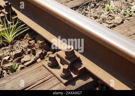 Rotaie fissate con viti alla traversina ferroviaria. Traversina ferroviaria in legno. Foto Stock
